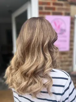 Natural-looking honey blonde Balayage Bognor Regis with soft waves for a professional, high-shine finish.