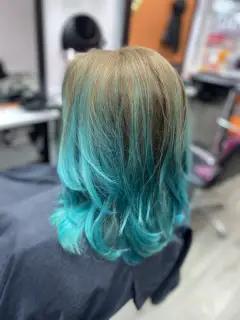 Creative teal and blue dip-dye hair colouring with face-framing layers, professional results in Bognor Regis.
